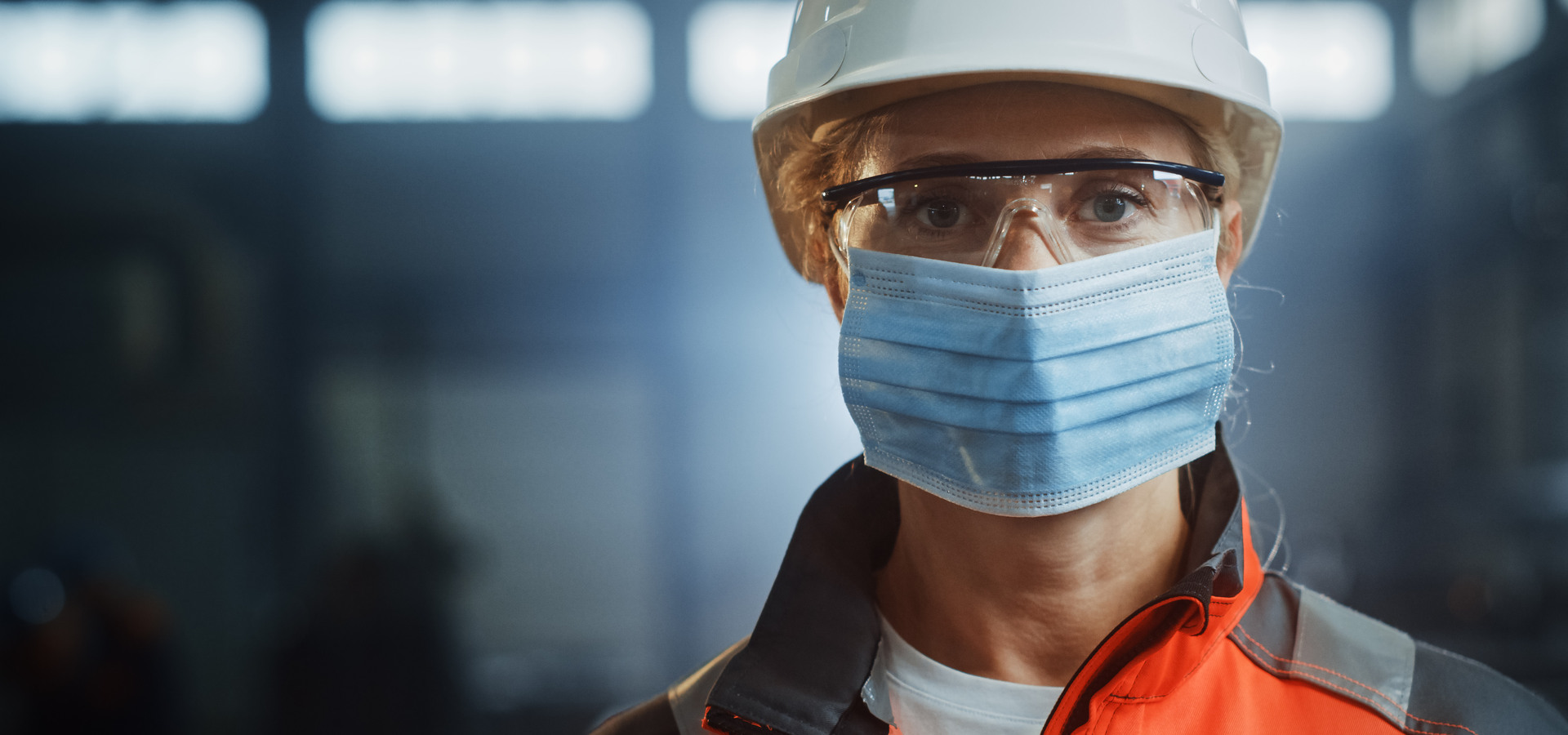 Portrait of a Professional Heavy Industry Engineer Worker Wearing on Safety Face Mask in a Steel Factory. Beautiful Female Industrial Specialist in Hard Hat Standing in Metal Construction Facility.