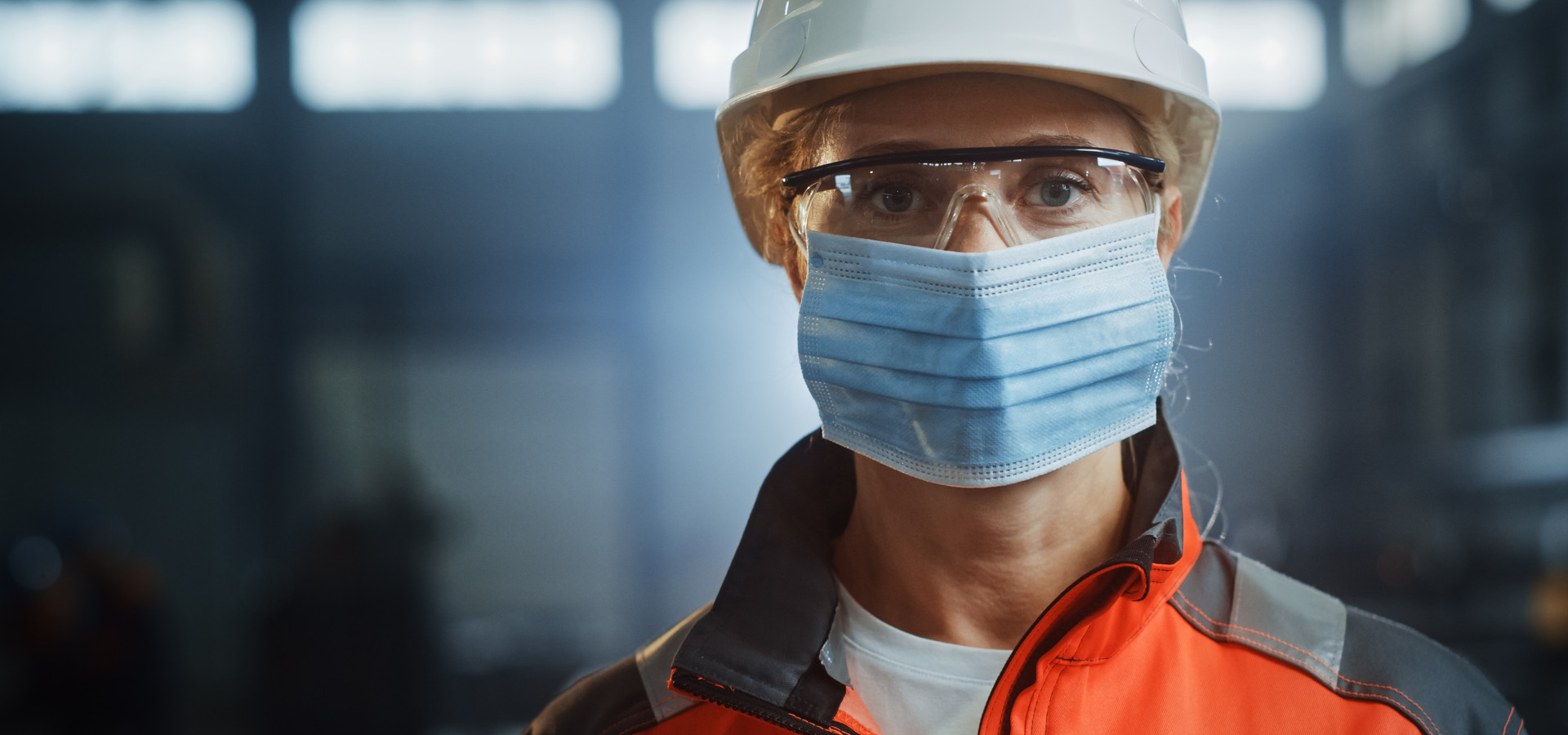 Portrait of a Professional Heavy Industry Engineer Worker Wearing on Safety Face Mask in a Steel Factory. Beautiful Female Industrial Specialist in Hard Hat Standing in Metal Construction Facility.