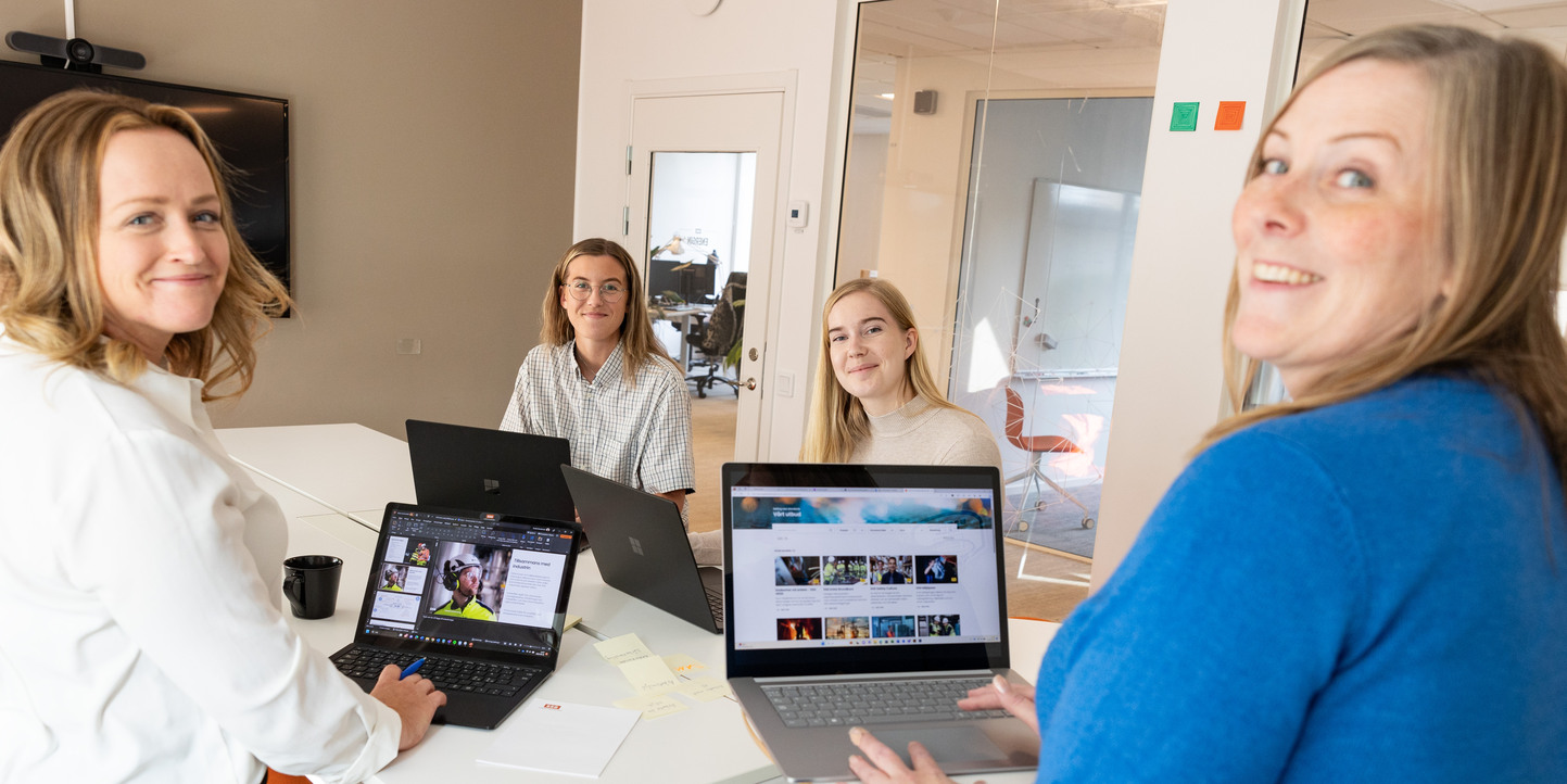 Fyra personer som står vid ett bord med sina datorer.