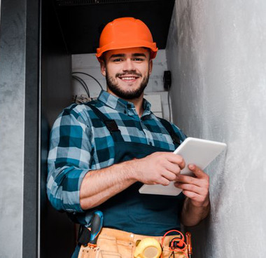 happy bearded technician in safety helmet holding digital tablet